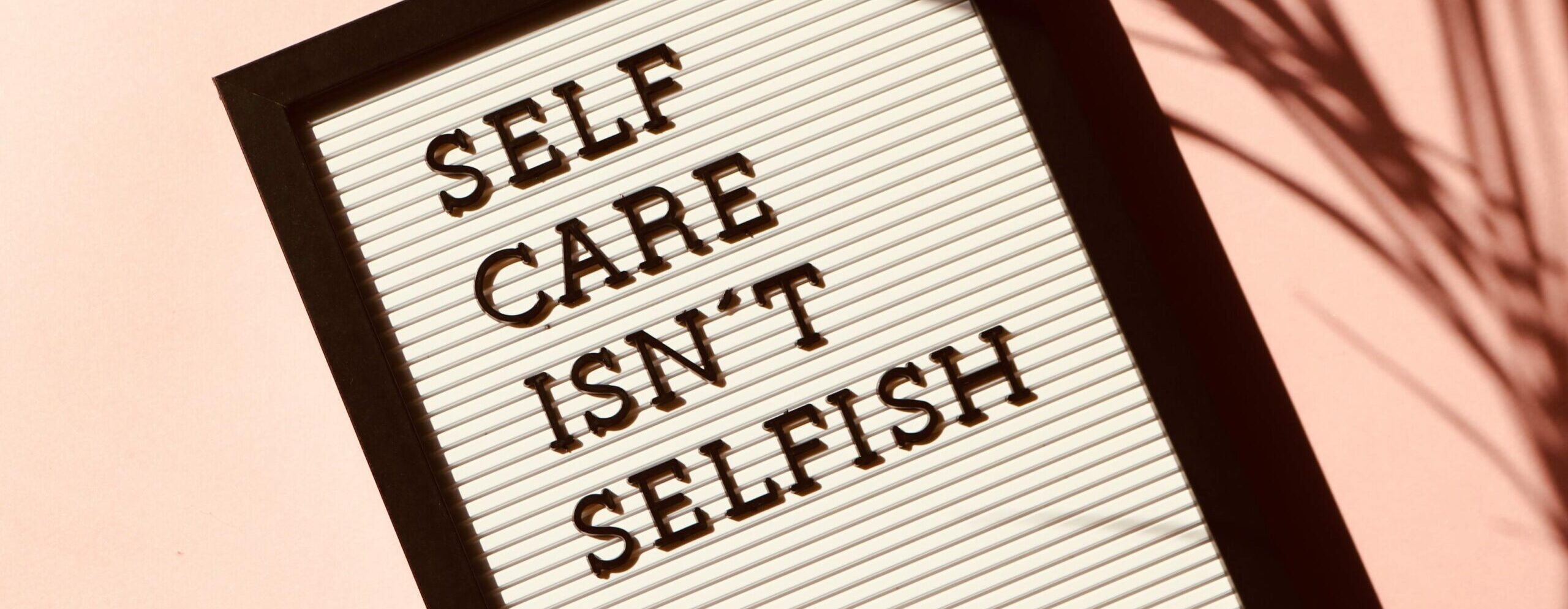 Foto met een bordje waar de tekst "self care isn't selfish" op staat. In het nederlands: Zelfzorg is niet egoïstisch"