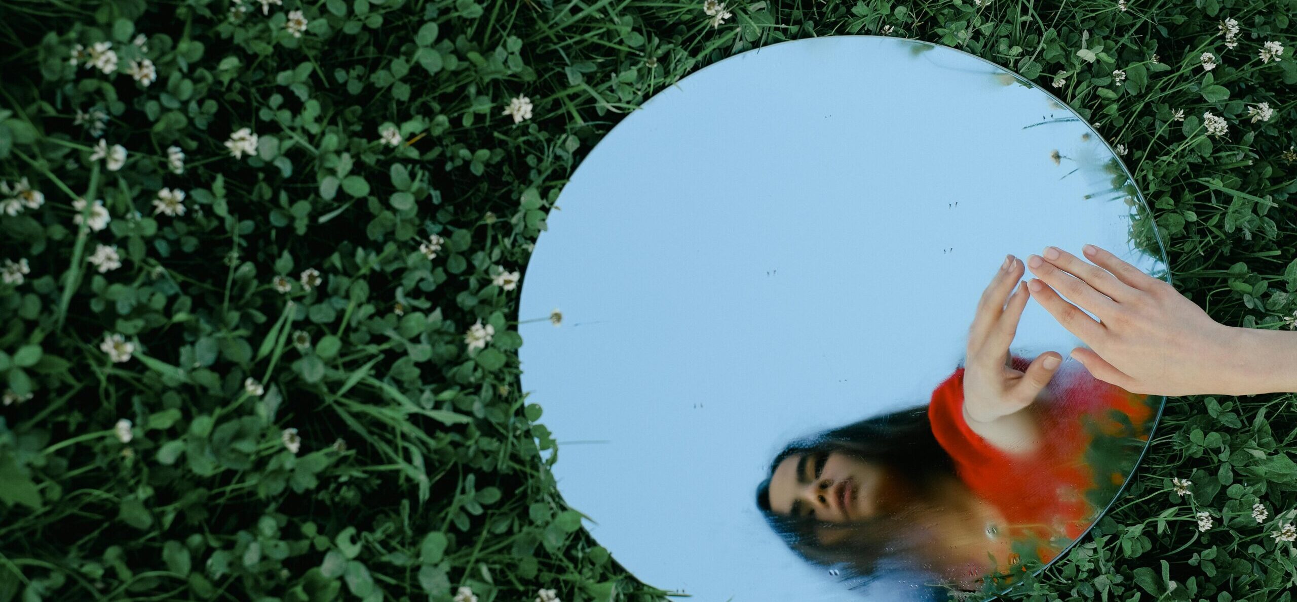 Foto van een spiegel in het glas met een hand erbij en een weerspiegeling van een meisje in de spiegel