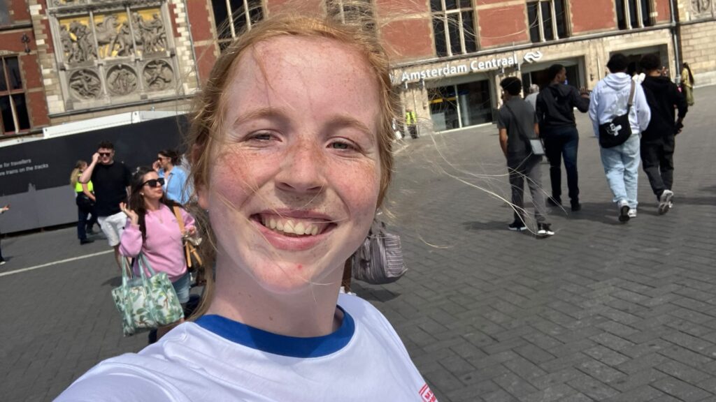 foto van jongpitter Merel voor een gebouw, op de achtergrond zie je mensen